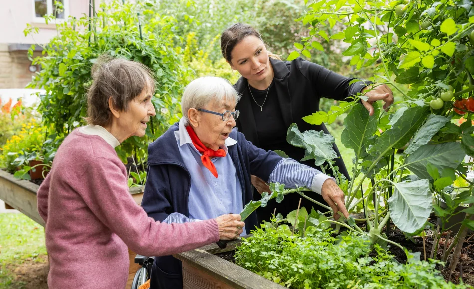 Bewohnerinnen und Pflegerin im Garten