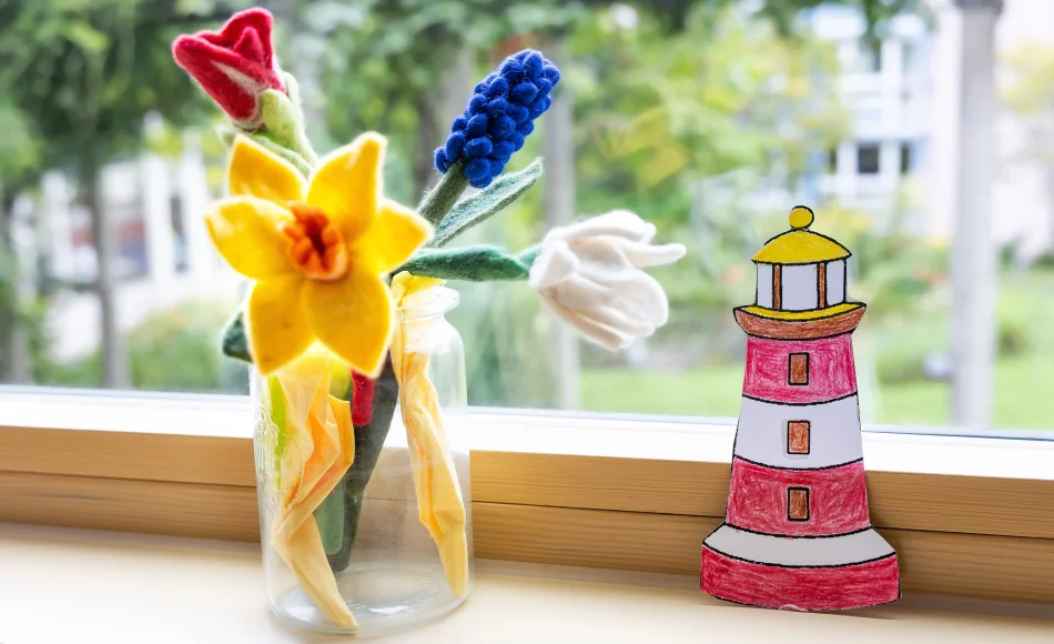 Filzblumen und ein gebastelter Leuchtturm auf dem Fensterbrett