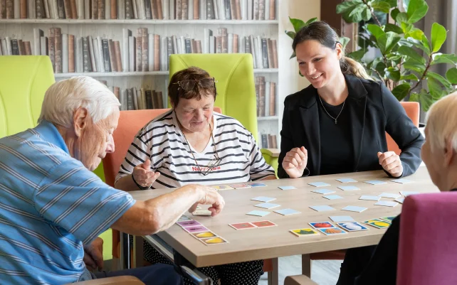 Besucher der Tagespflege spielen Memory mit einer Pflegerin