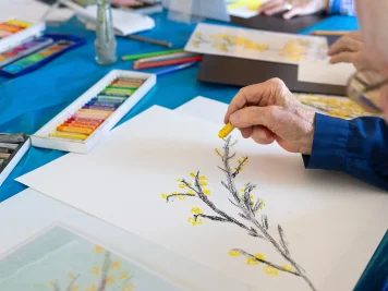 Eine ältere Frau malt einen blühenden Forsythienzweig