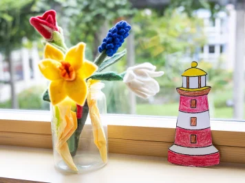 Filzblumen und ein gebastelter Leuchtturm auf dem Fensterbrett